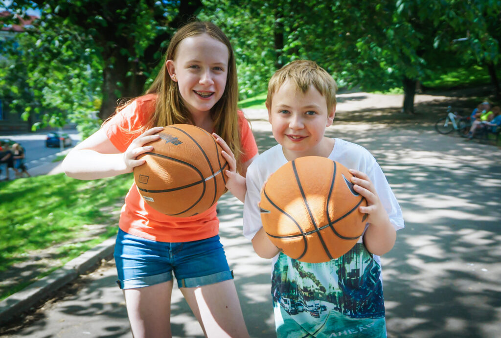 Jente og gutt med basketball utendørs