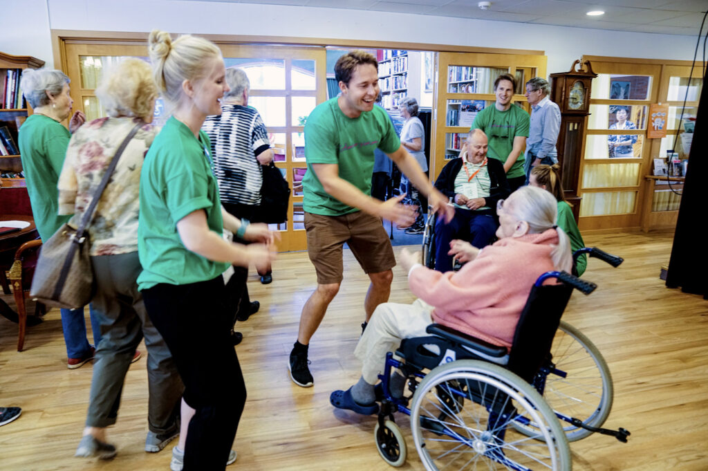 Eldres som danser med frivillige