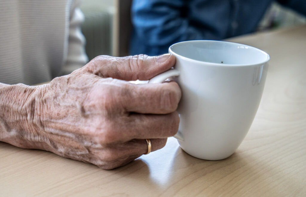 Eldres om holder en kaffekopp