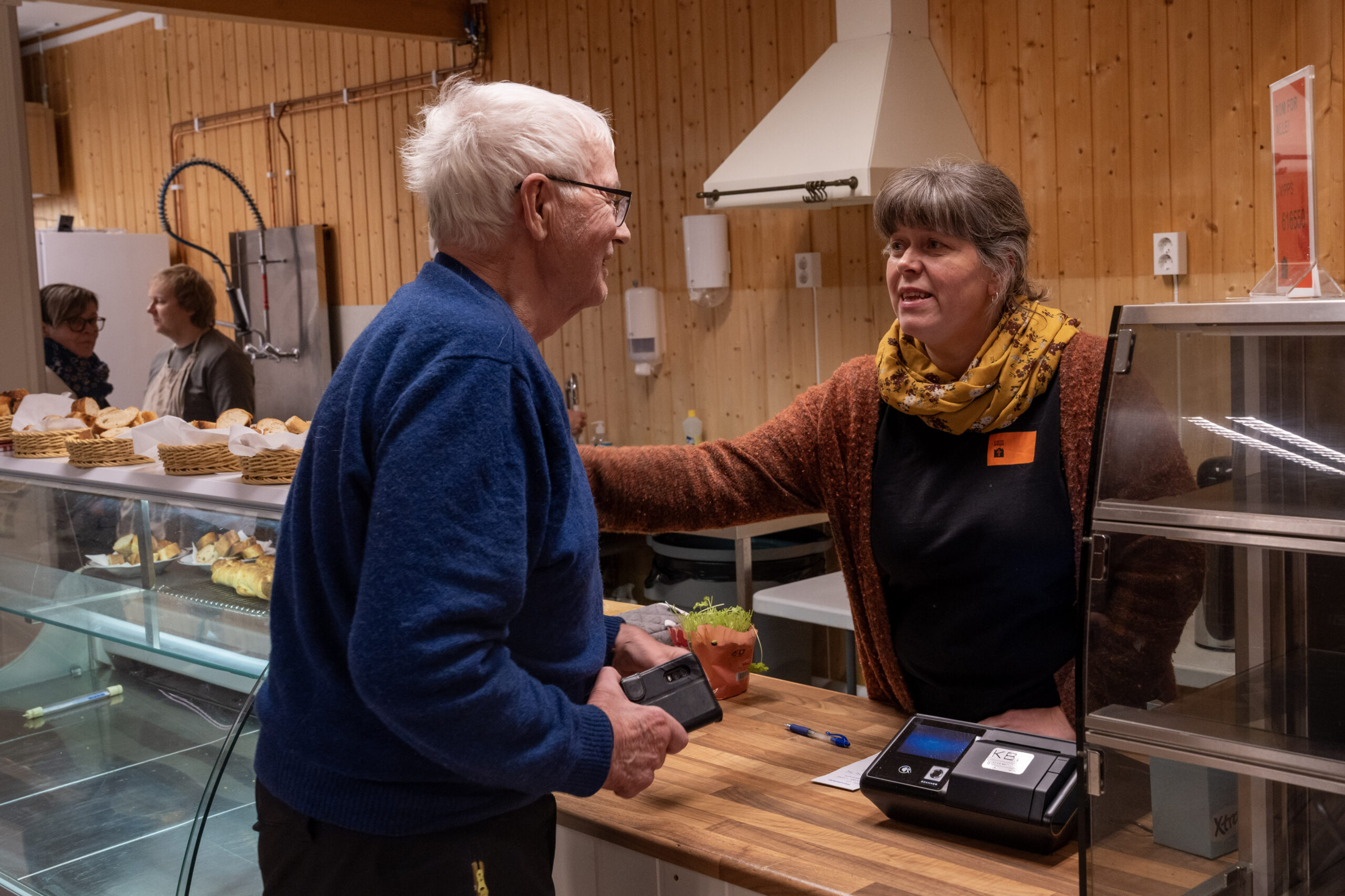 En eldre mann og voksen kvinne har en hyggelig samtale over kafédisken