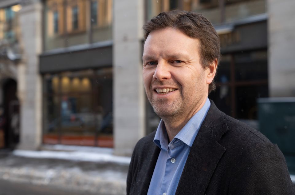 N&aelig;rbilde av assisterende generalsekret&aelig;r Ivar Stokkereit som smiler mot kamera, foran Kirkens Bymisjons hovedkontor i Tollbugata.