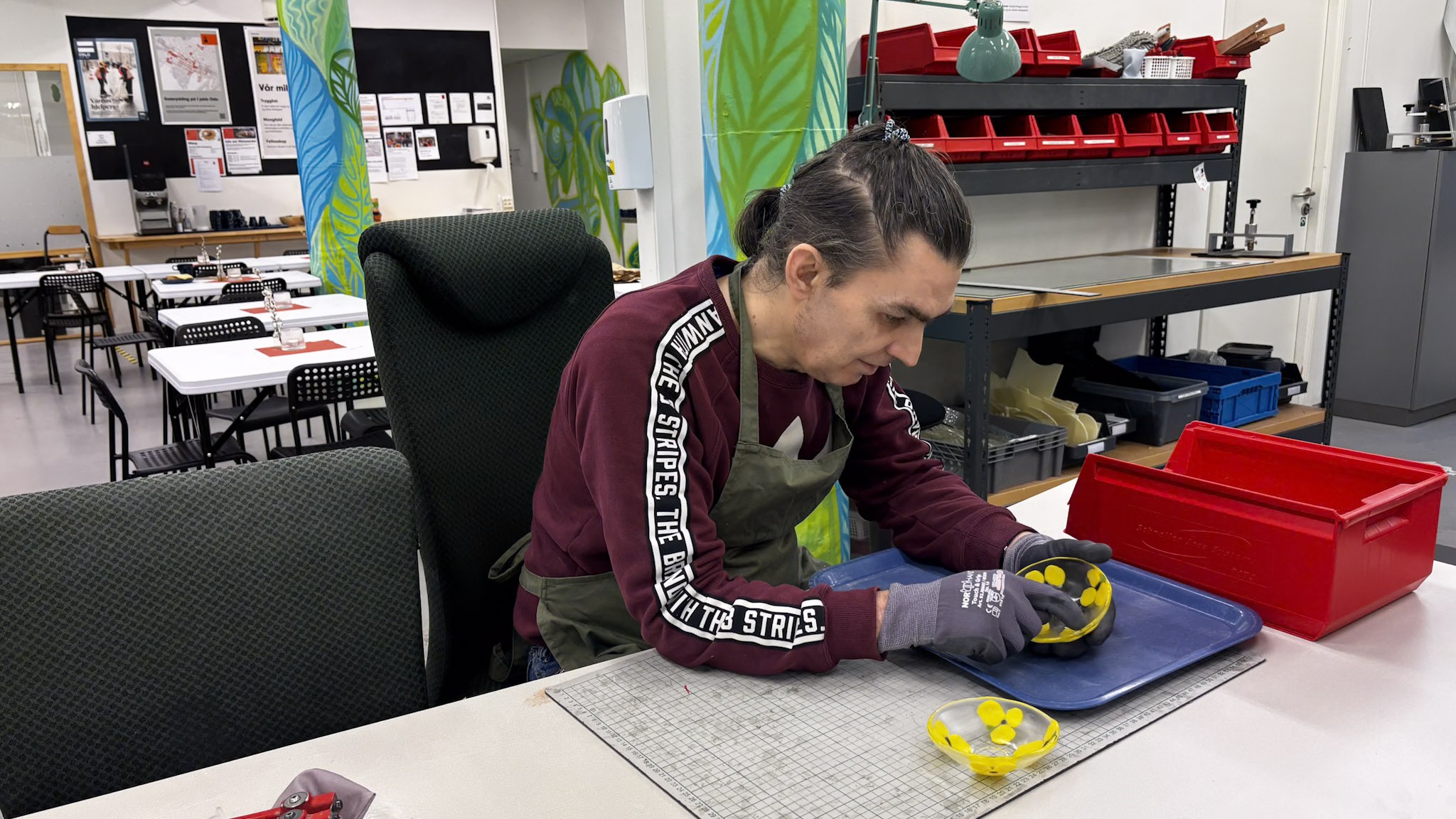 Bj&oslash;rn holder en glassk&aring;l malt med gule stemorsblomster.