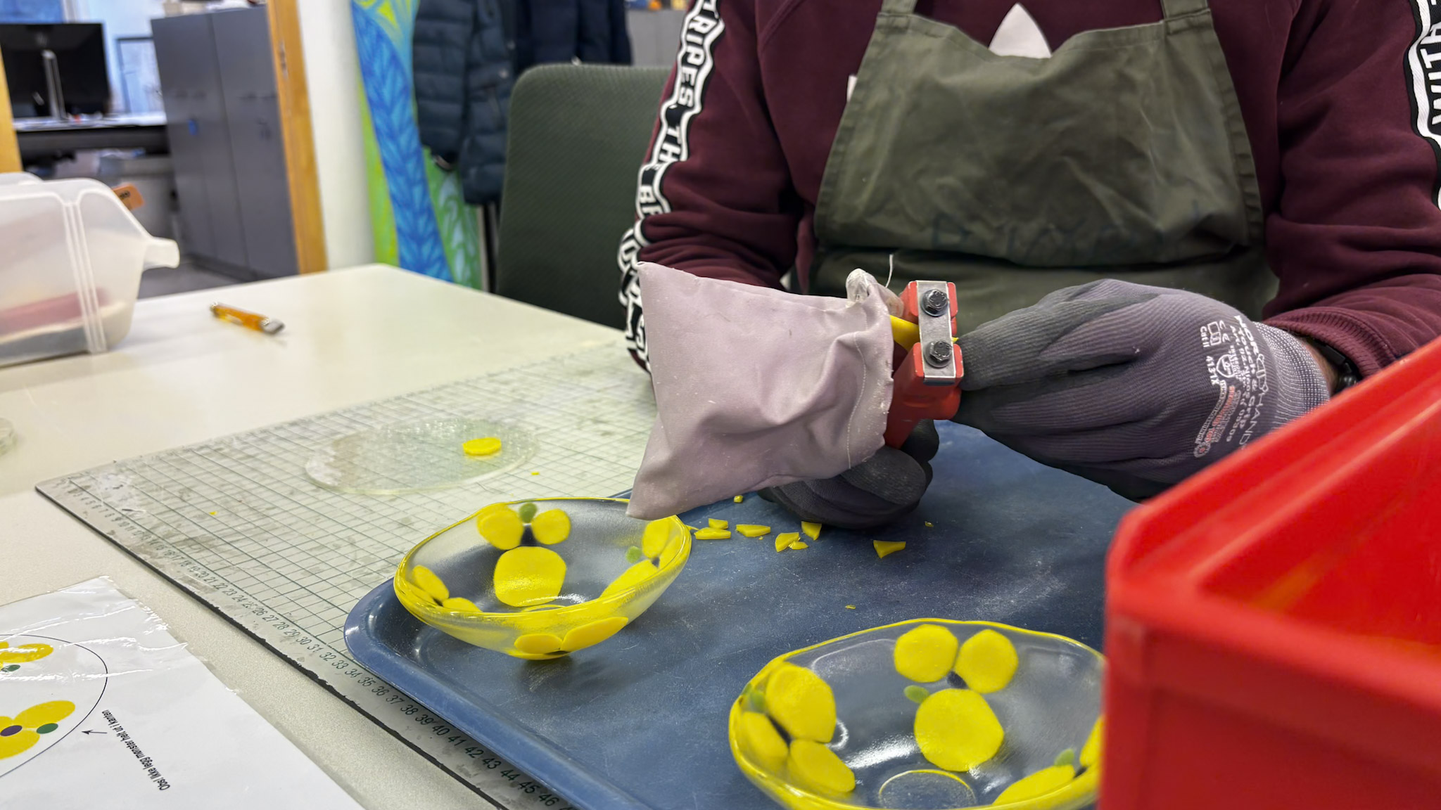 N&aelig;rbilde av to glassk&aring;ler malt med gule stemorsblomster, hendene til Bj&oslash;rn med klippetang i bakgrunn.