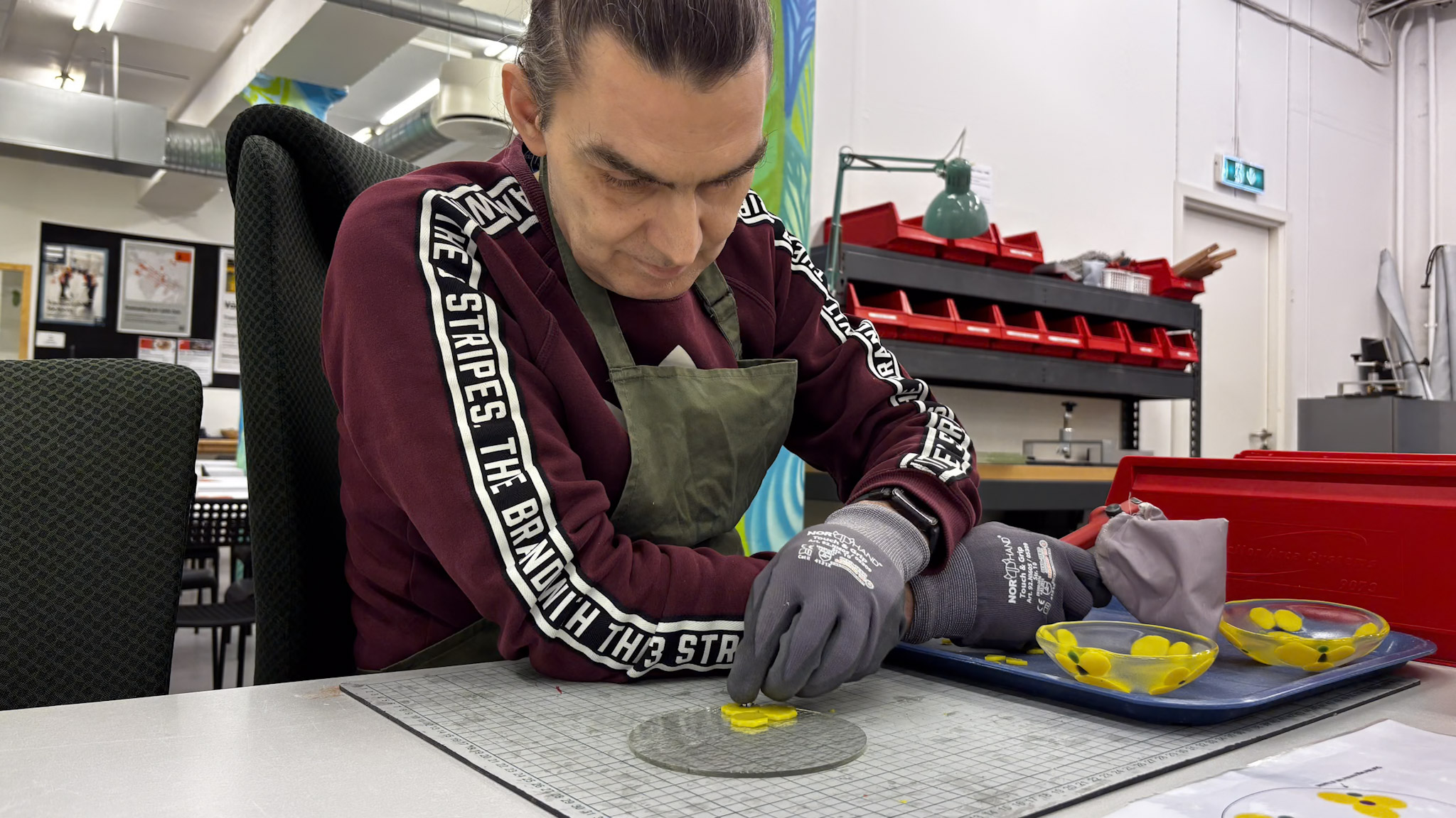 Bj&oslash;rn som konsentrerer seg om &aring; lage glassk&aring;l ved arbeidsbenken sin.