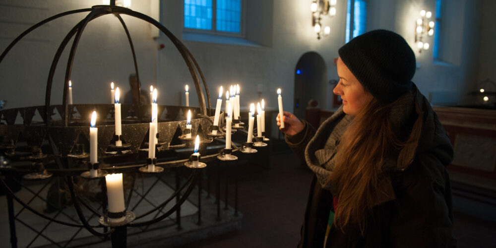 Kvinne som tenner lys i kirkerommet